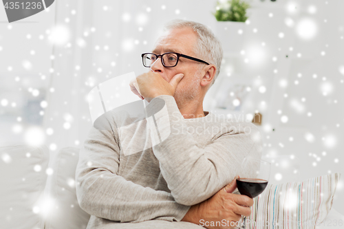 Image of senior man drinking red wine from glass at home