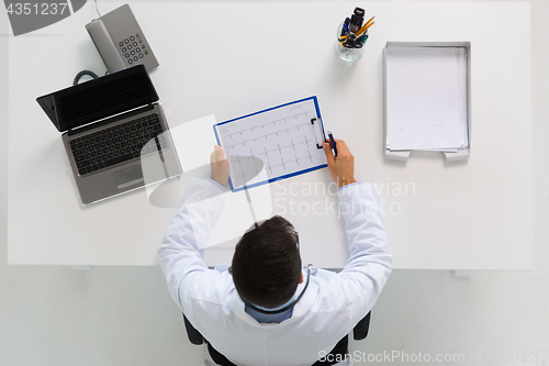 Image of doctor with cardiogram and laptop at clinic