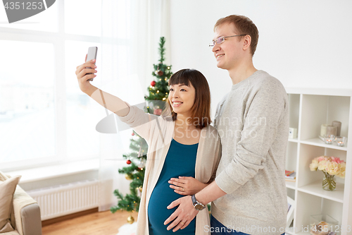 Image of happy family couple taking selfie at christmas