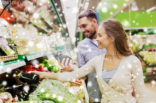 Image of happy couple buying eggplant at grocery store