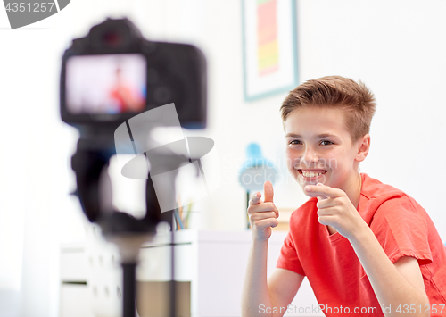 Image of happy boy with camera recording video at home