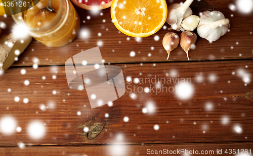 Image of honey, citrus fruits, ginger and garlic on wood