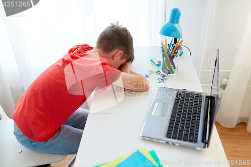 Image of tired or sad student boy with laptop at home