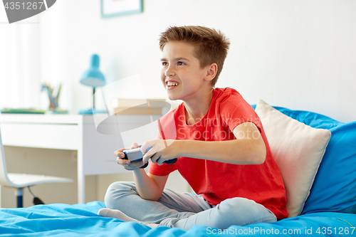 Image of happy boy with gamepad playing video game at home