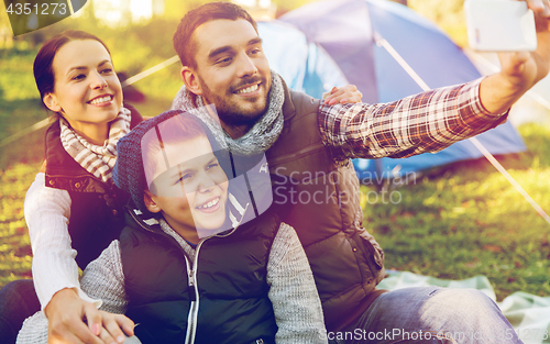 Image of family with smartphone taking selfie at campsite