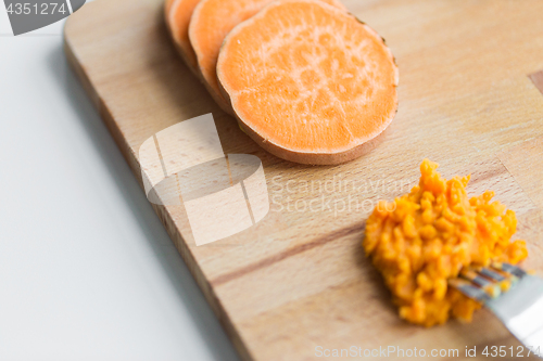 Image of hand with fork making mashed batata on board