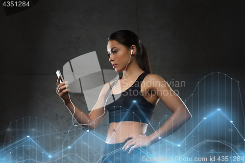 Image of woman with smartphone and earphones in gym