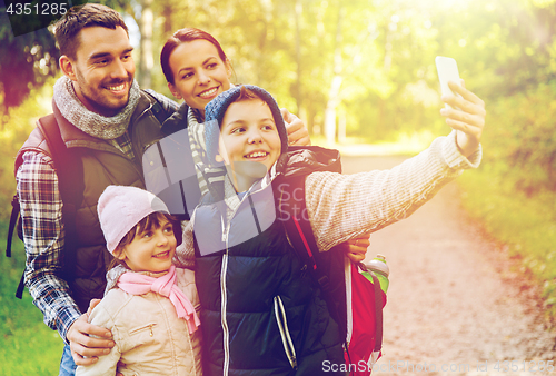 Image of family with backpacks taking selfie by smartphone