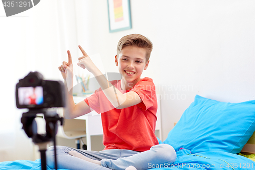 Image of happy boy with camera recording video at home