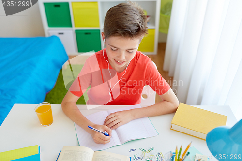 Image of happy student boy writing to notebook at home