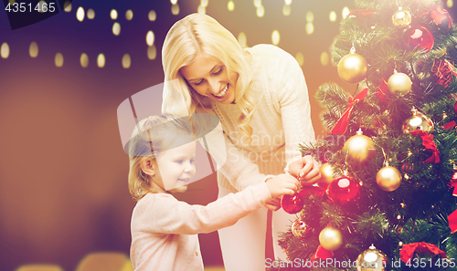 Image of mother and daughter decorating christmas tree