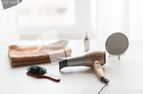 Image of hairdryer, hair brushes, mirror and towel