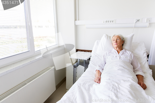 Image of sad senior woman lying on bed at hospital ward