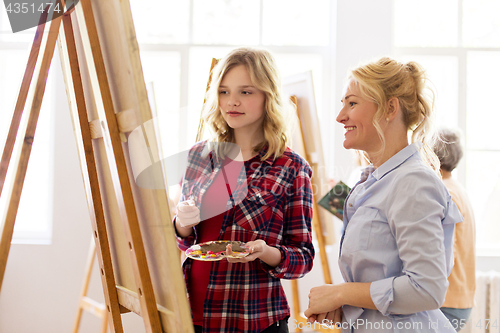 Image of artists discussing painting on easel at art school