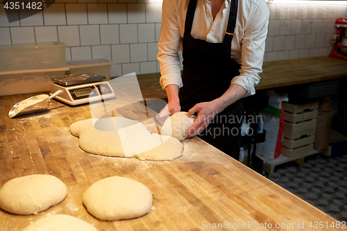 Image of baker portioning dough with bench cutter at bakery