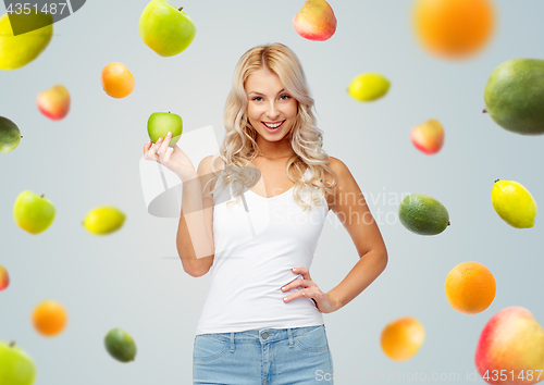 Image of happy beautiful young woman with green apple