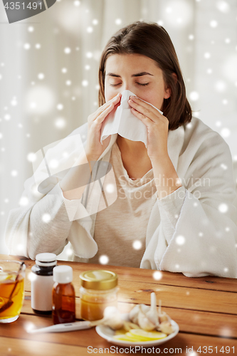 Image of sick woman with medicine blowing nose to wipe