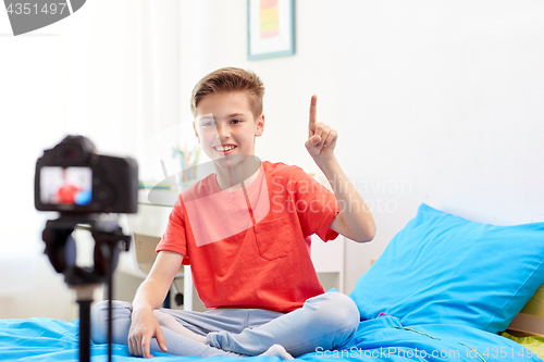 Image of happy boy with camera recording video at home