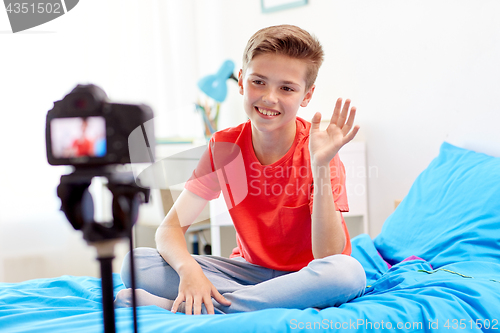 Image of happy boy with camera recording video at home