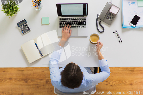 Image of businesswoman with laptop and coffee at office