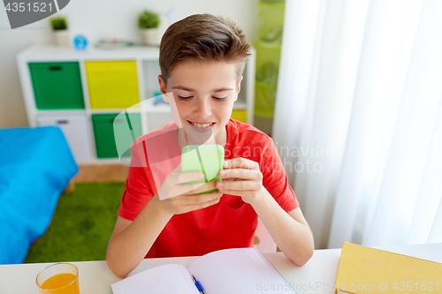 Image of student boy with smartphone distracting from study