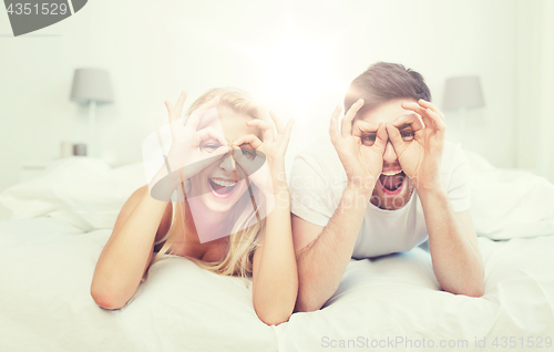 Image of happy couple lying in bed at home