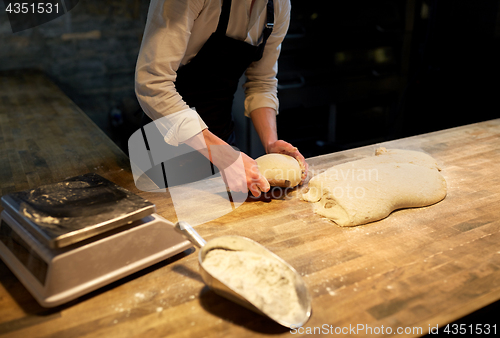 Image of baker portioning dough with bench cutter at bakery