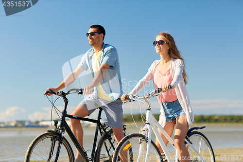 Image of happy young couple riding bicycles at seaside