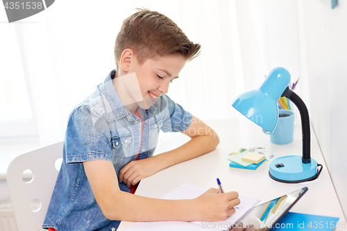 Image of happy student boy writing to notebook at home