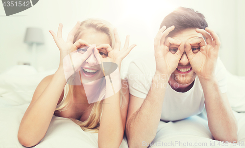 Image of happy couple lying in bed at home