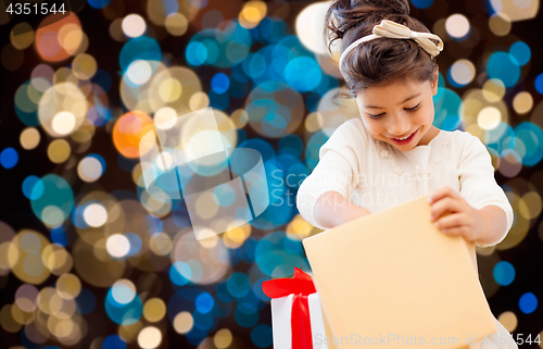 Image of smiling little girl with gift box over lights