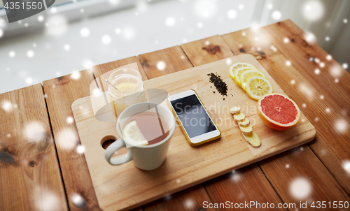 Image of smartphone with cup of lemon tea, honey and ginger