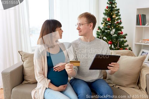 Image of man and pregnant wife shopping online at christmas