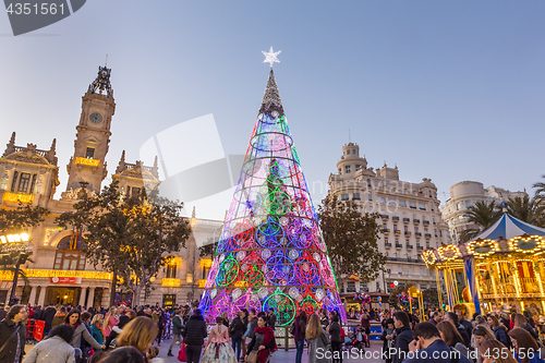 Image of Christmas fair with colorful christmas tree and carousel on Modernisme Plaza of the City Hall of Valencia, Spain.