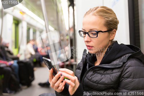 Image of Young girl reading from mobile phone screen in metro.