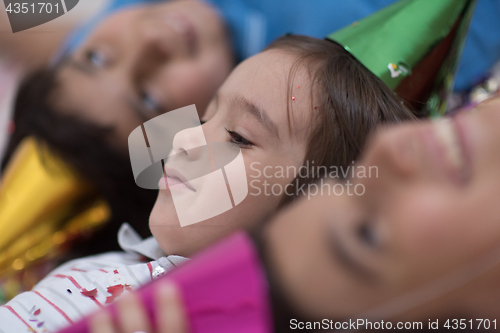 Image of kids  blowing confetti while lying on the floor