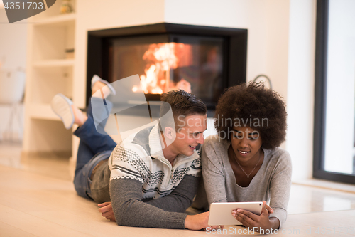 Image of multiethnic couple using tablet computer on the floor