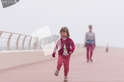 Image of mother and cute little girl on the promenade by the sea