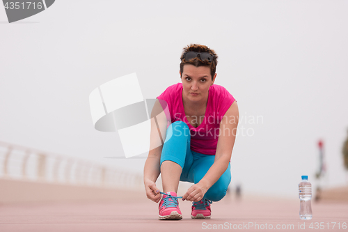 Image of Young woman tying shoelaces on sneakers