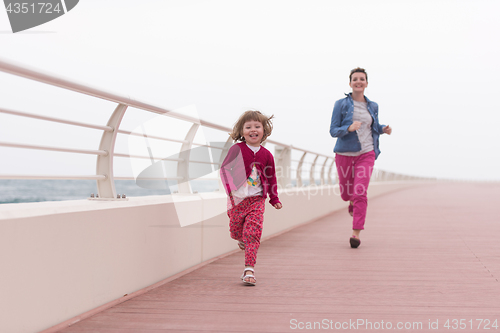 Image of mother and cute little girl on the promenade by the sea