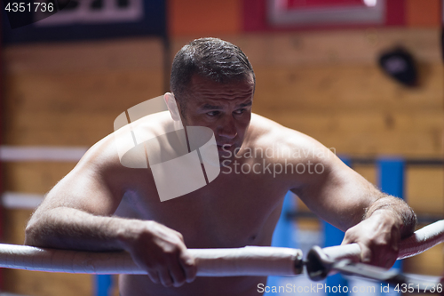 Image of kick boxer resting on the ropes in the corner