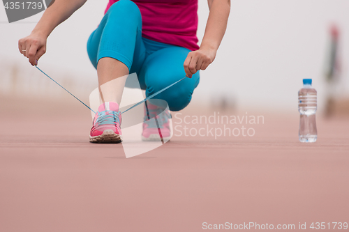 Image of Young woman tying shoelaces on sneakers