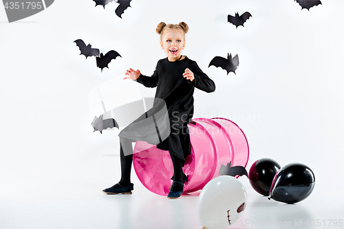 Image of Little girl witch in black dress over magical accessories. Halloween, the studio evening.