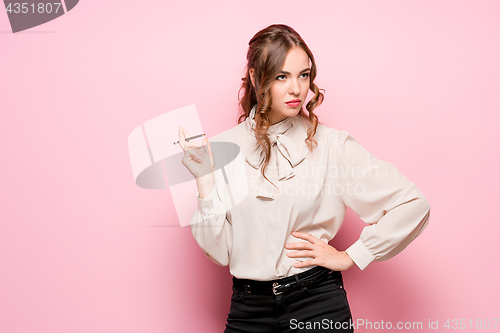 Image of The serious frustrated young beautiful business woman on pink background