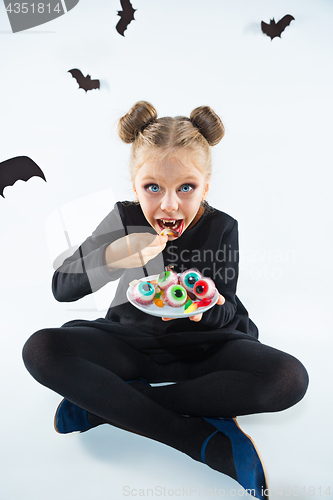 Image of Little girl witch in black dress over magical accessories. Halloween, the studio evening.