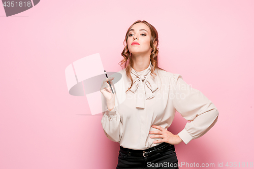 Image of The serious frustrated young beautiful business woman on pink background