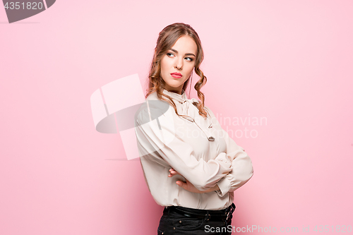 Image of The serious frustrated young beautiful business woman on pink background