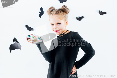 Image of Little girl witch in black dress over magical accessories. Halloween, the studio evening.