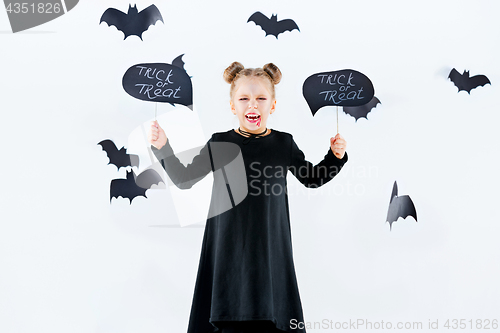 Image of Little girl witch in black dress over magical accessories. Halloween, the studio evening.