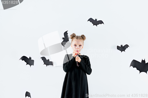 Image of Little girl witch in black dress over magical accessories. Halloween, the studio evening.